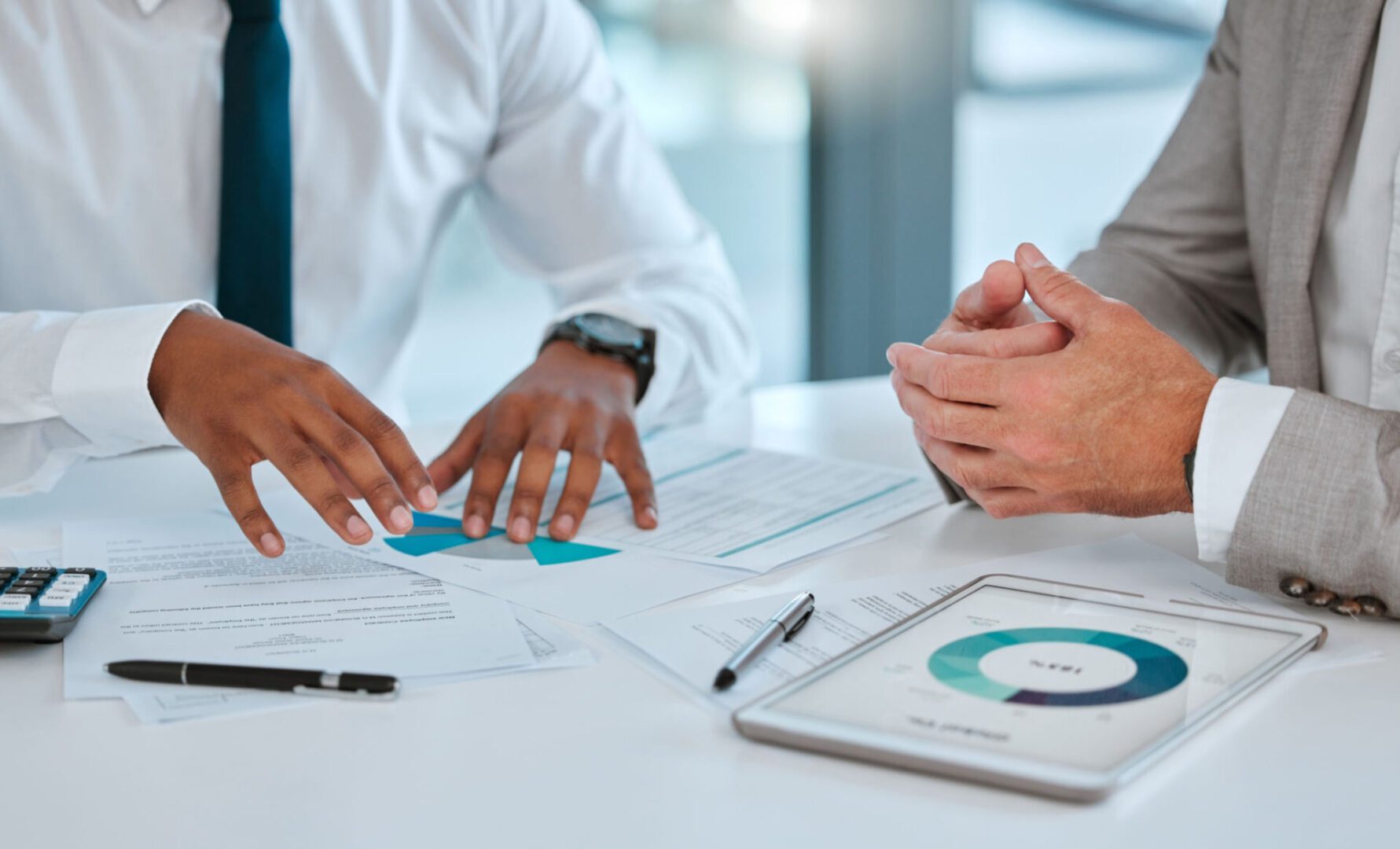 Two people discussing documents and tablet charts.