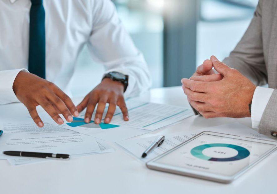 Two people discussing documents and tablet charts.